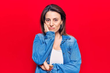 Genç ve güzel bir kadın günlük kıyafetler giyip kollarını kavuşturarak depresyondan sıkılmış ve yorgun görünüyor.. 