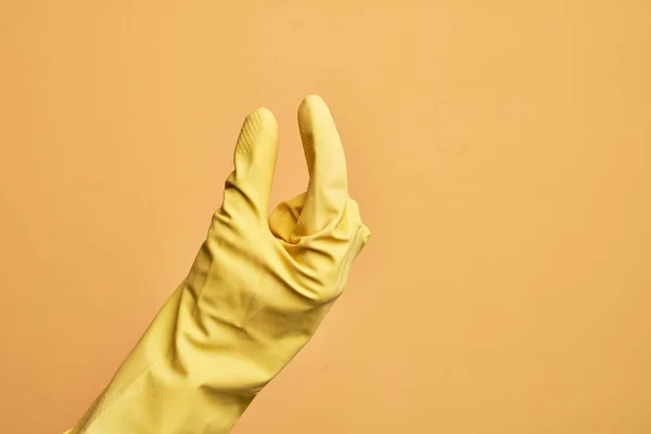 白人年轻人的手 戴着清洁手套 穿过孤立的黄色背景 拿起看不见的东西 手拿着显示空间的东西 — 图库照片