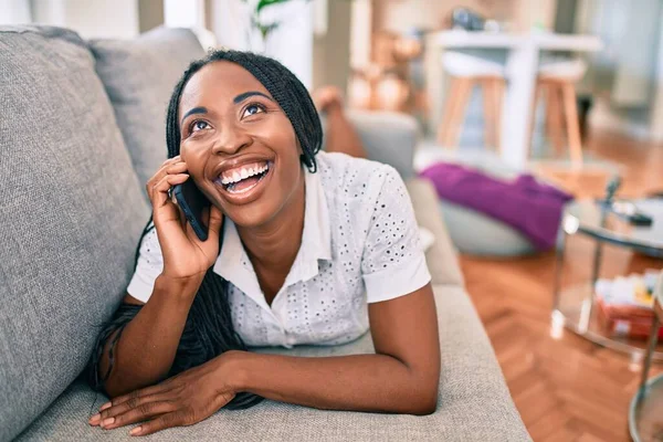 Joven Mujer Afroamericana Sonriendo Feliz Usando Teléfono Inteligente Acostado Sofá —  Fotos de Stock