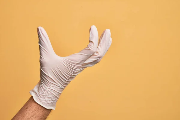 Mão Jovem Caucasiano Com Luva Médica Sobre Fundo Amarelo Isolado — Fotografia de Stock