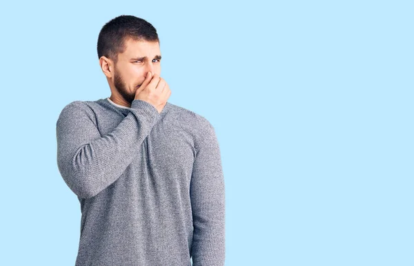 若いハンサムな男は 鼻の上に指で息を保持し 臭いと嫌な 耐え難い臭い何かを嗅ぐカジュアルなセーターを着て 臭いが悪い — ストック写真