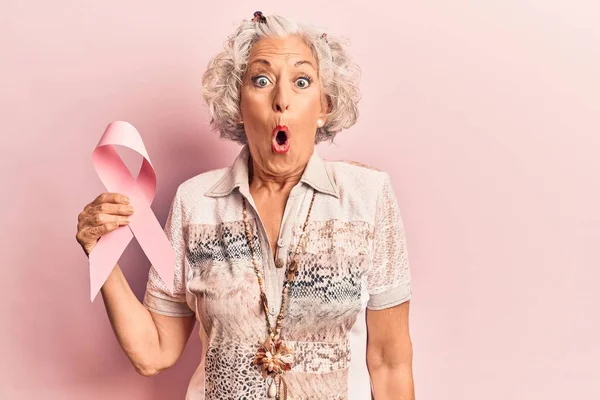高个子白发苍苍的女人 拿着粉红的癌症彩带 惊慌失措 张大了嘴 满脸诧异 — 图库照片