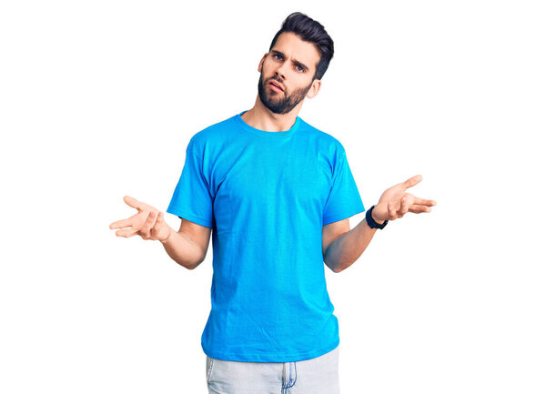 Young handsome man with beard wearing casual t-shirt clueless and confused with open arms, no idea concept. 