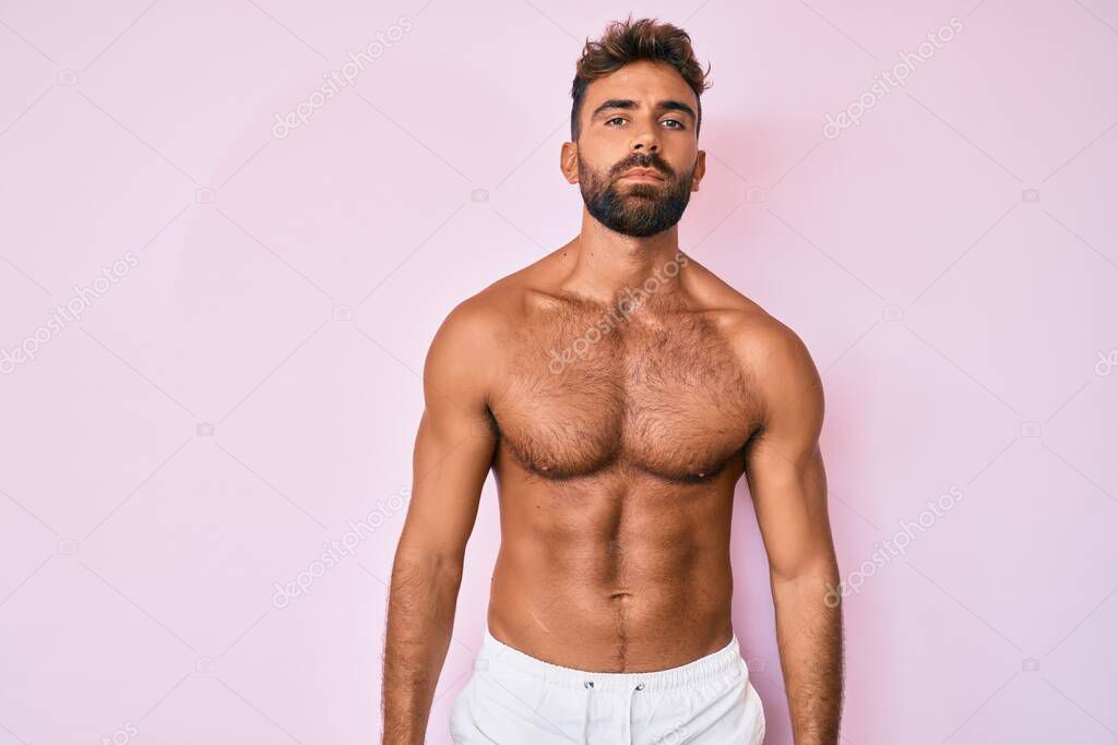 Young hispanic man standing shirtless relaxed with serious expression on face. simple and natural looking at the camera. 