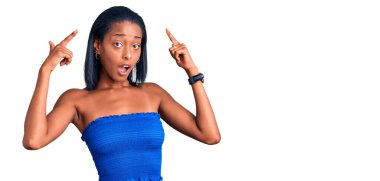 Genç Afrikalı Amerikalı kadın, günlük kıyafetlerini giyiyor. İki eliyle başını gösteren gülümsemeler, harika bir fikir ya da düşünce, iyi bir hafıza. 