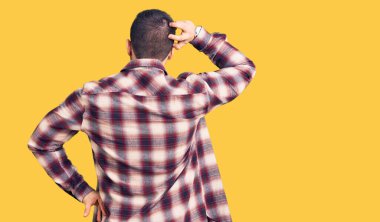 Genç ve yakışıklı bir adam gündelik gömleği ters giyip elleri kafasında şüpheyi düşünüyor. 