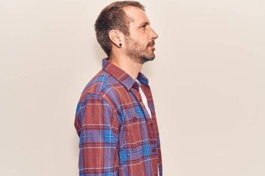 Sıradan kıyafetler giyen genç yakışıklı bir adam, rahat bir görünüm takınıyor kendine güvenen bir gülümsemeyle doğal bir yüz ifadesi takınıyor.. 