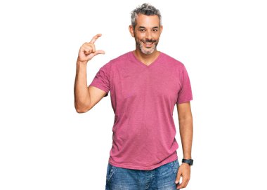 Orta yaşlı, gri saçlı, günlük kıyafetler giyen, gülümseyen, kendine güvenen, el hareketi yapan, parmaklarıyla işaret yapan ve kameraya bakan bir adam. ölçüm kavramı. 