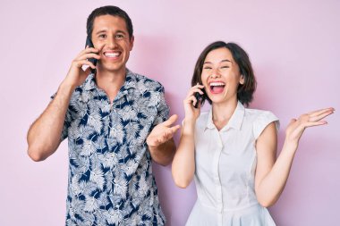Akıllı telefonda konuşan güzel bir çift zaferi mutlu bir gülümsemeyle kutluyor ve kazanan el kaldırarak ifade ediyor. 