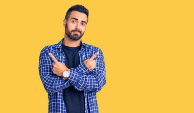 Gündelik kıyafetler giyen genç İspanyol adam her iki tarafı da parmaklarıyla işaret ediyor, farklı yönlerde farklı görüşler. 