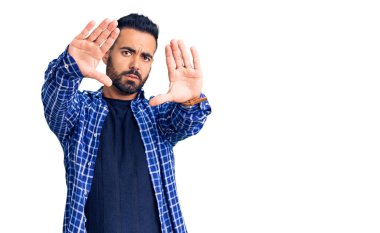 Gündelik kıyafetler giyen, el ve parmaklarını kullanarak çerçeve yapan genç İspanyol adam, kamera açısı. 