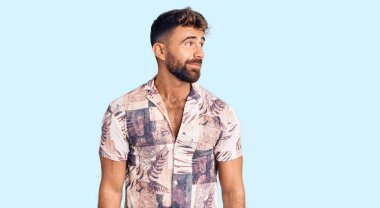 Yazlık kıyafetler giyen genç İspanyol adam gülümseyip yan tarafa bakıyor ve düşünüyor.. 