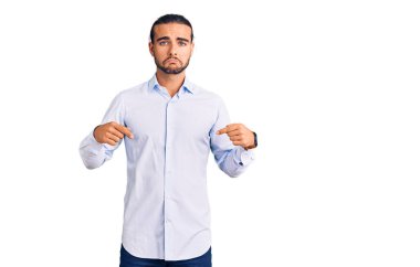 İş kıyafetleri giymiş genç yakışıklı adam üzgün ve üzgün görünüyor, parmaklarıyla yön gösteriyor, mutsuz ve depresif. 