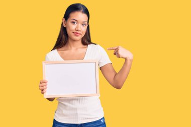 Genç, güzel Latin kız elinde boş beyaz karatahta tutarak mutlu ve gururlu bir kendini işaret ediyor. 