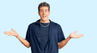 Gündelik kıyafetler giyen genç yakışıklı adam zaferi mutlu bir gülümsemeyle ve kazanan yüz ifadesiyle kutluyor. 