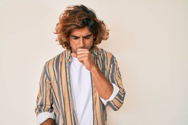 Günlük kıyafetler giyen genç İspanyol adam kendini iyi hissetmiyor ve soğuk algınlığı veya bronşitin belirtisi olarak öksürüyor. sağlık hizmeti kavramı. 