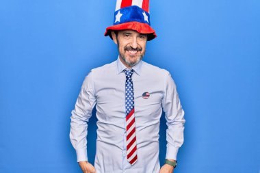 Orta yaşlı, yakışıklı, vatansever, şapkalı, mavi arka planda kravat takan mutlu ve havalı bir yüzü olan bir adam. Şanslı kişi..