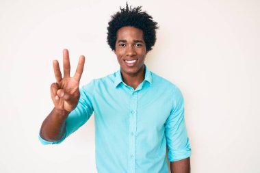 Yakışıklı, Afro saçlı, sıradan giyinmiş, üç numarayı işaret eden, kendinden emin ve mutlu gülümseyen Afro-Amerikan adam.. 