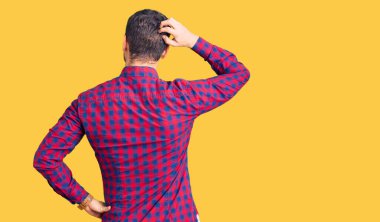 Ayılı yakışıklı genç adam, rahat gömleğini ters giymiş, elleri kafasında şüpheyi düşünüyor. 