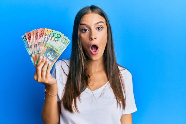 Genç İspanyol kadın Avustralya doları tutuyor. Korkmuş ve ağzı açık kalmış, şaşırmış ve şaşırmış. 