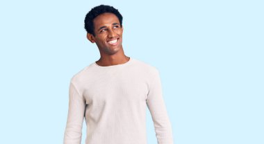 Sıradan bir kazak giyen Afrikalı yakışıklı bir adam yüzünde gülümseme, doğal bir ifade ile yan yana bakıyor. Kendinden emin gülen. 