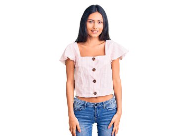 Gündelik kıyafetler giyen genç, güzel bir Latin kız. Pozitif ve mutlu görünüyor. Kendine güvenen bir gülümsemeyle dişlerini gösteriyor. 