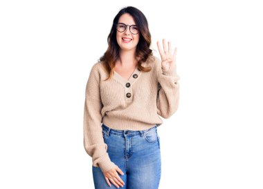 Güzel, genç, esmer bir kadın günlük kıyafetler ve gözlük takıyor. Dört numarayı gösteriyor ve işaret ediyor. Kendinden emin ve mutlu bir şekilde gülümsüyor.. 