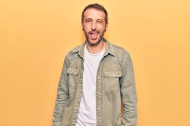 Gündelik kıyafetler giyen genç yakışıklı adam kameraya seksi bir ifadeyle bakıyor, neşeli ve mutlu bir yüzle.. 