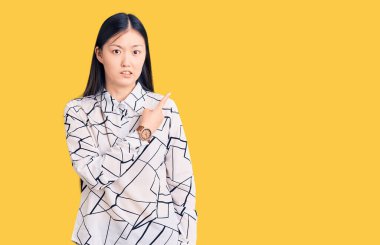 Genç, güzel Çinli kadın, rahat gömleğini giyip endişeli ve gergin bir şekilde işaret ediyor. 