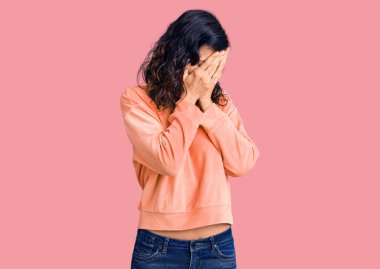 Genç, güzel, İspanyol bir kadın. Günlük kıyafetler giyiyor. Ağlarken suratını ellerle kapatıyor. depresyon kavramı. 