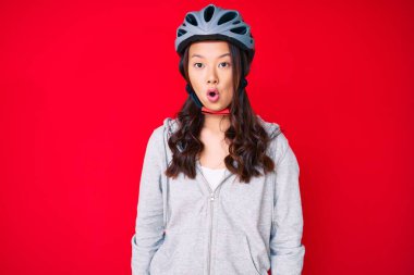 Bisiklet kaskı takan genç, güzel Çinli bir kız. Korkmuş ve ağzı açık kalmış, şaşırmış ve şaşırmış. 