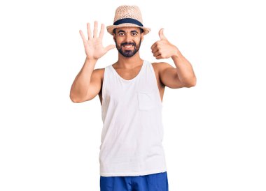 Gündelik yaz şapkası takan İspanyol genç adam altı numarayı gösterip işaret ederken kendinden emin ve mutlu bir şekilde gülümsüyor.. 
