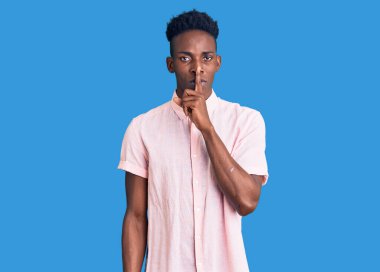 Gündelik giysiler giymiş genç Afro-Amerikan bir adam sessiz olmak istiyor. sessizlik ve gizli konsept. 