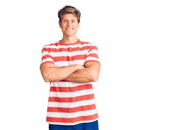 Sıradan kıyafetler giyen, kollarını kavuşturup kameraya bakan mutlu yüzlü genç bir adam. pozitif kişi. 