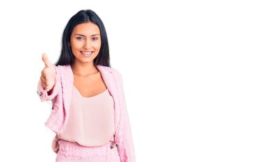 İş kıyafetleri içinde genç ve güzel bir Latin kız gülümseyerek dostça el sıkışmayı karşılama ve hoş geldin olarak sunuyor. başarılı iş. 