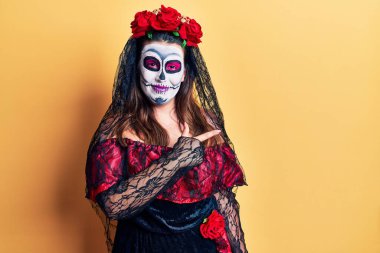 Ölü kostümü giyen genç bir kadın. Yüzünde mutlu ve doğal bir ifadeyle el ve parmak ile işaret eden bir gülümseme. 