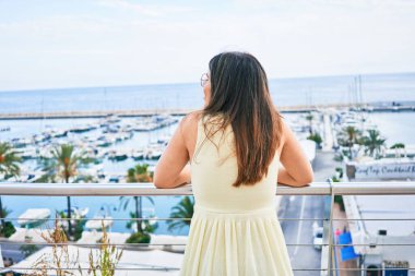 Arkadan bakan genç İspanyol kadın Balustrade görünümlü liman manzarasına yaslanıyor.