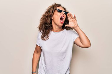 Orta yaşlı güzel bir kadın beyaz arka planda komik haydut gözlüğü takıyor ve avazı çıktığı kadar bağırıyor. İletişim konsepti.