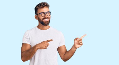 Gündelik kıyafetler giyen, gözlüklü, gülümseyen ve kameraya bakan genç İspanyol bir adam.. 