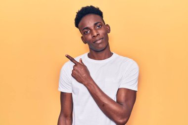 Genç Afro-Amerikalı, günlük kıyafetler giymiş, elini kaldırmış, ciddi ve sakin bir yüz ifadesi sergiliyor. 