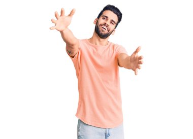 Sakallı, sıradan tişörtlü genç yakışıklı kameraya sarılıp gülümsüyor. Mutluluğu kucaklayan neşeli bir ifade.. 