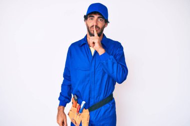 Kıvırcık saçlı ve ayı gibi giyinen yakışıklı genç adam sessiz olup dudaklarını öpmek istiyor. sessizlik ve gizli konsept. 