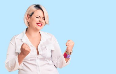 Kolları havada, gözleri kapalı zaferi kutlarken gülümseyen gündelik gömlek giyen genç sarışın ve cüsseli bir kadın. Kazanan konsept. 