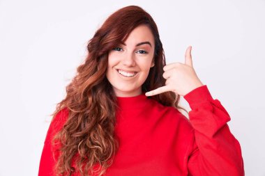 Genç, güzel bir kadın, günlük kıyafetler giyip gülümsüyor telefonla el ve parmaklarıyla jest yapıyor telefonda konuşuyor gibi. iletişim kavramları. 