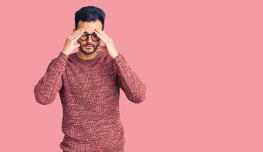 Kışlık süveter giyen, başı ağrıyan, eli başında gözlük takan genç, yakışıklı İspanyol bir adam. migren ağrısı. 