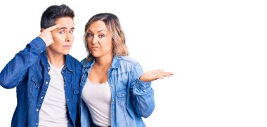 Sıradan kıyafetler giyen, avuç içi açık fotokopi alanı gösteren ve alnını işaret eden iki kadın. Bunu bir düşün.. 