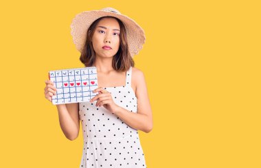 Yaz şapkası takan genç, güzel Çinli bir kız. Elinde kalp takvimi, düşünceli bir tavır ve kendine güvenen bir ifade var. 