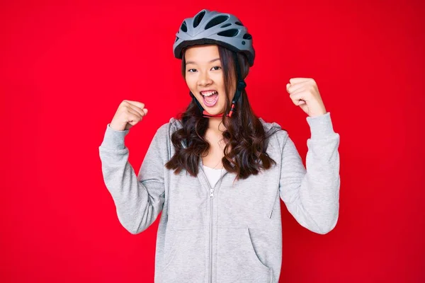 若い美しい中国の女の子は誇りに思って叫んで自転車ヘルメットを身に着けています 勝利と成功を祝います非常に腕を上げ興奮 — ストック写真