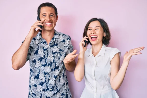 Akıllı telefonda konuşan güzel bir çift zaferi mutlu bir gülümsemeyle kutluyor ve kazanan el kaldırarak ifade ediyor. 