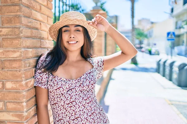 Tatildeki genç Latin kadın gülümsüyor. Şehrin duvarına yaslanmaktan mutlu..